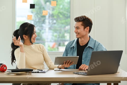 Preview: Two smiling coworkers are discussing project, working together in modern creative office.