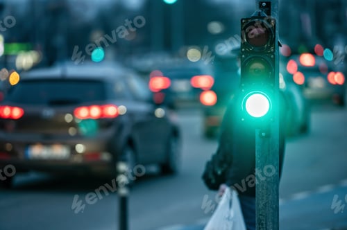 Preview: a city crossing with a semaphore on blurred background with cars in the evening streets, green light