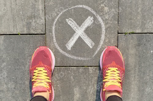 Preview: Checkmark no sign on gray sidewalk with woman legs in sneakers, top view