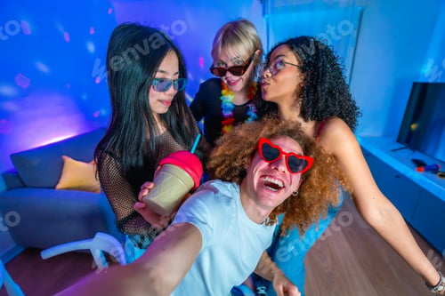 Preview: Friends taking a selfie at home party with colorful lights and drinks