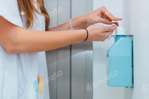Preview: Medic in white coat disinfecting hands in clinic
