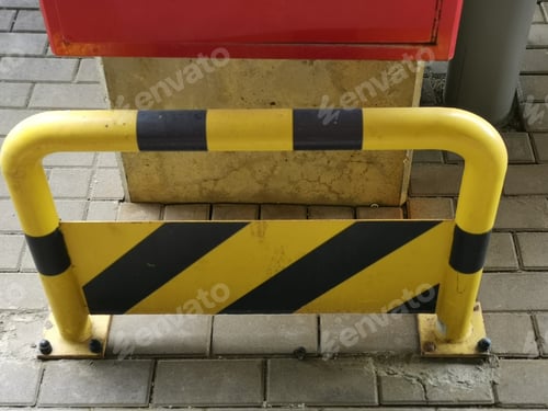 Preview: Yellow safety barrier with black stripes put outside by the stone pillar