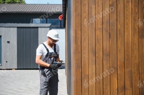 Preview: Construction worker preparing drill next to wooden wall