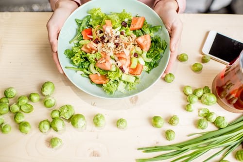 Preview: Holding a plate with green salad on the table