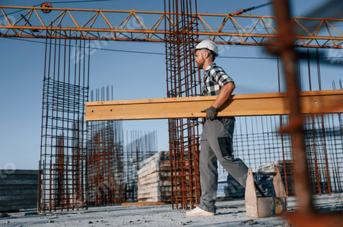 Preview: Walking and holding wooden plank. Man is working on the construction site at daytime