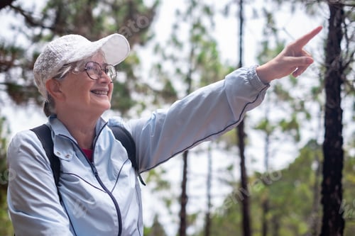 Preview: Portrait of happy active senior woman walking in a mountain forest enjoying nature
