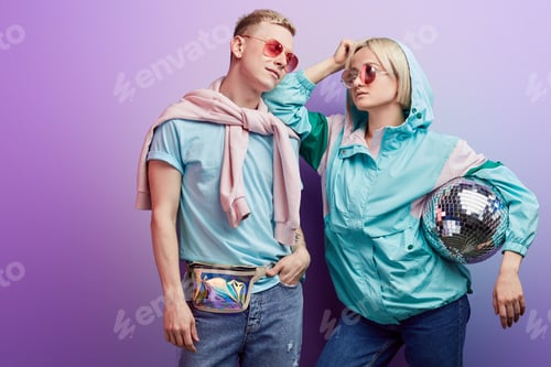 Preview: Young fashionable couple of dancers posing with disco ball on violet background