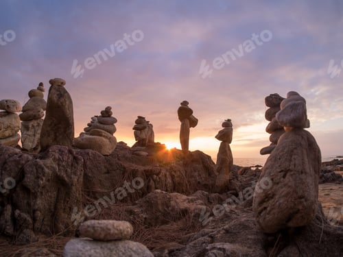 Preview: Stones pyramid on sand symbolizing zen, harmony, balance. Ocean at sunset