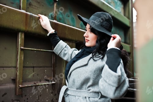 Preview: Brunette girl in gray coat with hat in railway station.