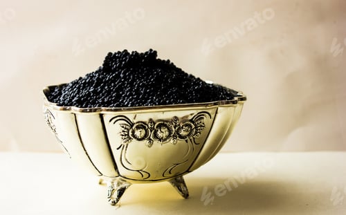 Preview: Black caviar in a bowl with lemon close up over dark background, top view