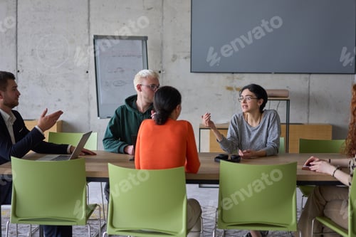 Preview: A young, diverse business team sitting together in a modern office, exchanging ideas and business