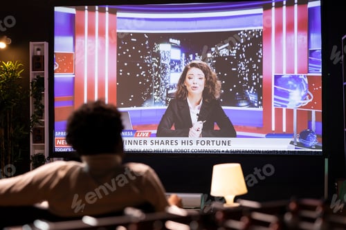 Preview: Cord cutter sitting on couch in front of widescreen smart TV displaying streamed news program