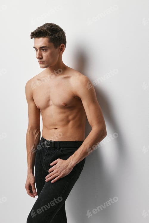 Preview: A guy in black trousers stands against a wall in a cropped view