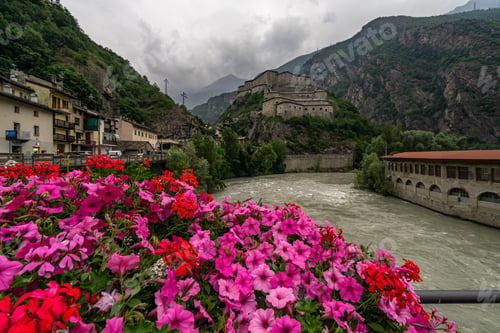 Preview: Bright red and pink petunia flowers in front of Fort Bard, Aosta Valley, Italy