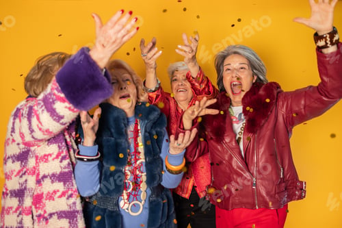 Preview: Group of senior women celebrating with falling confetti on yellow background