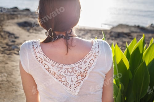 Preview: back view of a girl sitting on the sandy beach alone on the sea background close