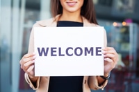 Preview: Smiling Woman Holding Welcome Sign in Office