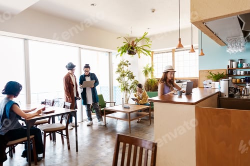 Preview: Group of young Japanese professionals working on laptop computers in a co-working space.