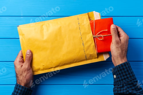 Preview: Male hands packing yellow bubble envelopes for shipping.