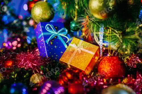 Preview: Christmas gift boxes in gold and blue lie next to tinsel and Christmas balls