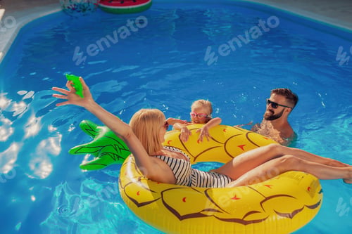 Preview: Mother, father and daughter playing at the swimming pool