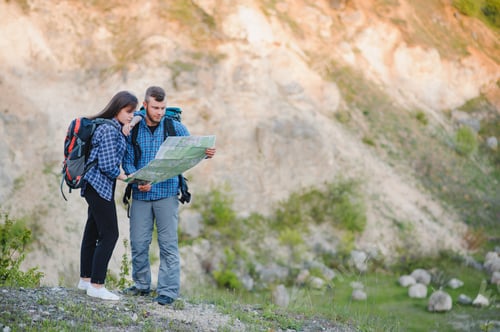 Preview: Happy romantic Couple Man and Woman Travelers with backpack holding hands mountaineering