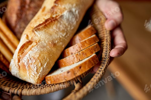 Preview: Close yp of man hand, holding basket with various bread freshly baked.