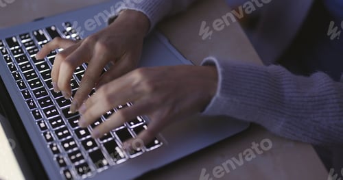 Preview: Woman typing on laptop computer in the evening at home