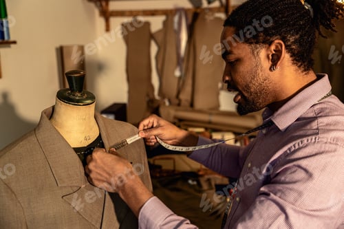 Preview: Male fashion tailor working on the measurements for the suit design in his workshop.