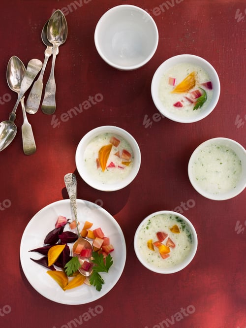 Preview: A table laid with small round white china bowls. Fresh food on a red background.