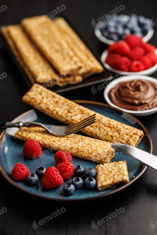 Preview: Delicate crepes stacked with blueberries and raspberries, served with a chocolate spread.