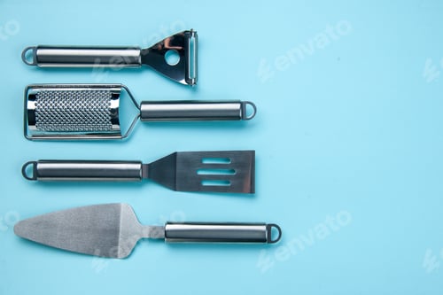 Preview: Horizontal view of stainless kitchen tools lying side by side on soft blue color background with