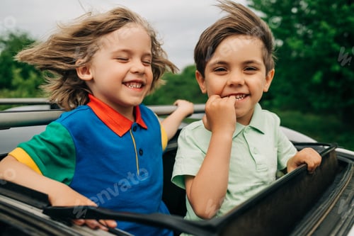 Preview: Adorable happy little boys children in open car sunroof during road trip