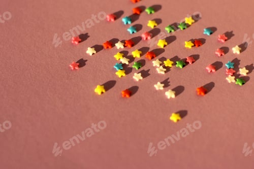 Preview: festive pink background with scattered small multicolored stars. confectionery sprinkles