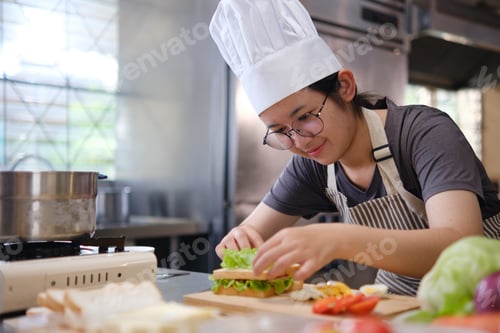 Preview: Focused chef carefully a gourmet sandwich in a professional kitchen with fresh ingredients in view