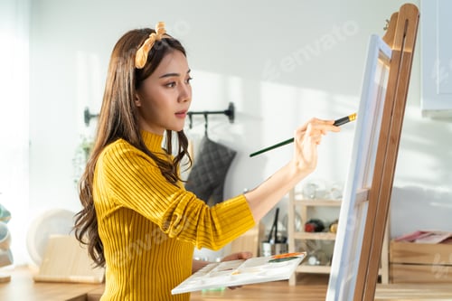 Preview: Asian young talented woman artist coloring on painting board in house.