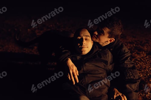 Preview: Men hugging and sitting on ground on field at night