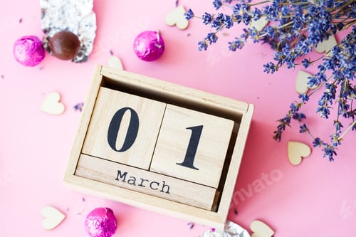 Preview: Wooden calendar with the date of March 1 on a pink background, a place for an inscription