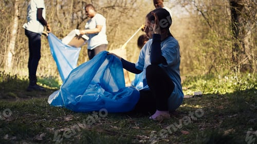 Preview: Tired little girl collecting trash and plastic bottles from the forest