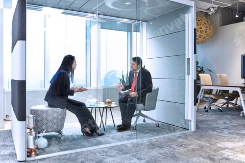 Preview: Colleagues having meeting in glass pod in office