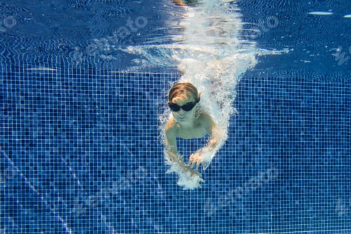 Preview: Smiling boy swimming underwater in pool