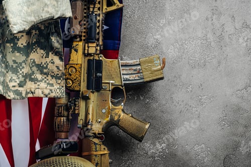 Preview: U.S. battle flag and assault rifle near the wall. close up