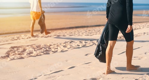 Preview: Two volunteer asian men collecting trash into plastic bag black for cleaning the beach in morning