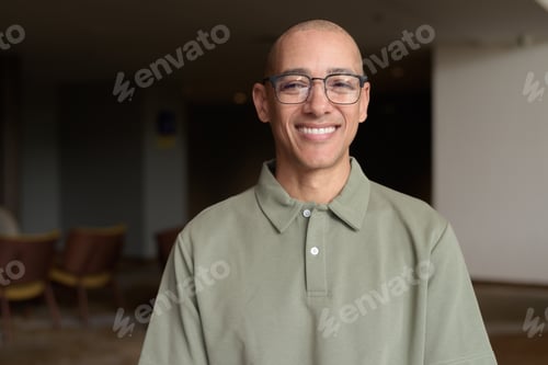 Preview: Bald Hispanic man in hotel lobby with eyeglasses, stylish confident portrait in casual setting