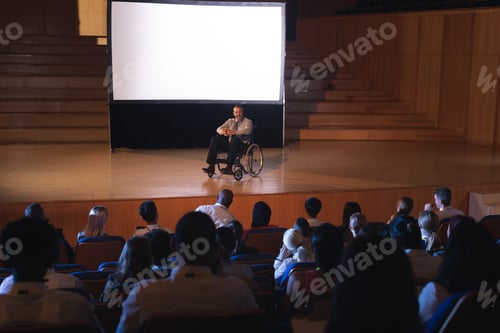 Preview: Businessman sitting on a wheelchair and giving presentation to the audience in the auditorium