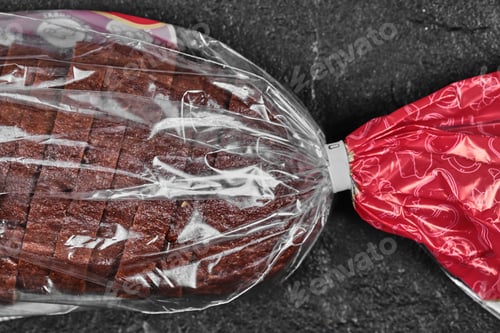 Preview: Sliced black rye bread in plastic bag on dark background