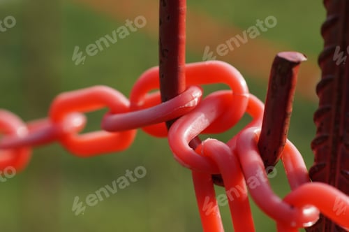 Preview: Closeup shot of red plastic barrier chains on rusted metal