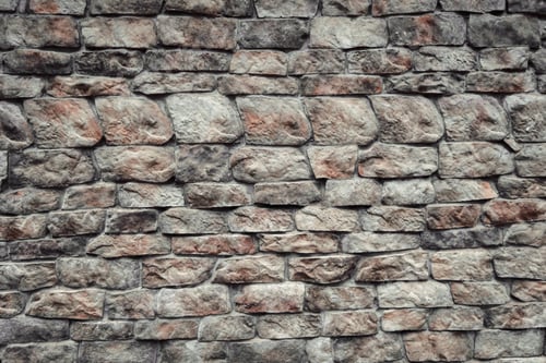 Preview: Textured stone wall with varying colors and shapes in an outdoor setting during daylight