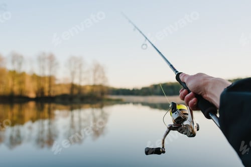 Preview: Fisherman with fishing rod in his hand catches fish on a boat. Fishing Day. Spinning in hand on pond