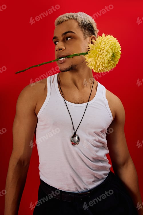 Preview: Young man flaunts trendy style with a flower in a red studio photoshoot